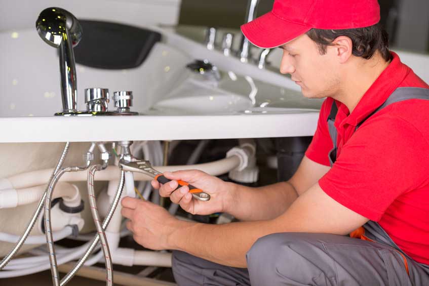 Male plumber fixing sink pipe in the bathroom